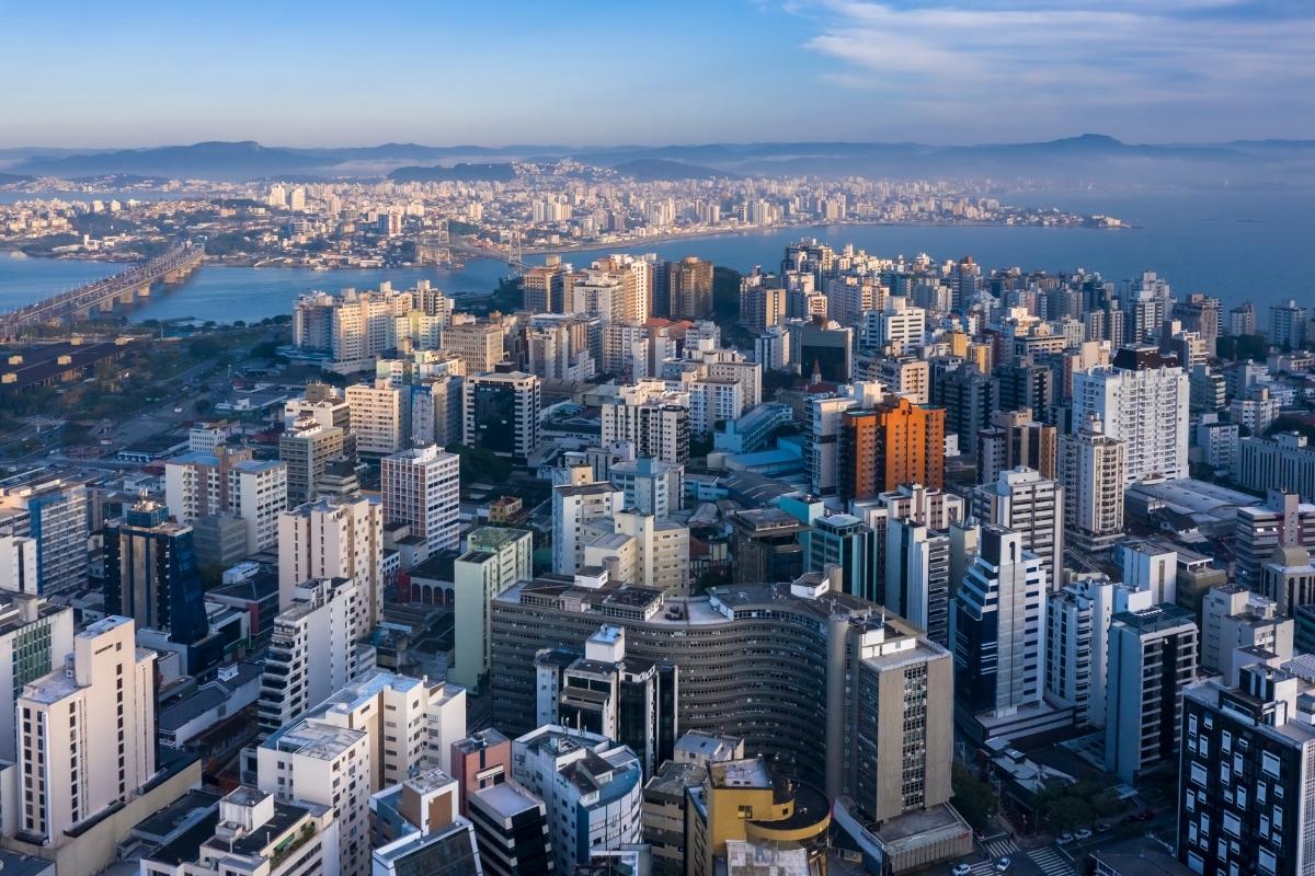 imagem aérea do Centro de Florianópolis com o edifício Ceisa em primeiro plano e as pontes e o continente ao fundo.